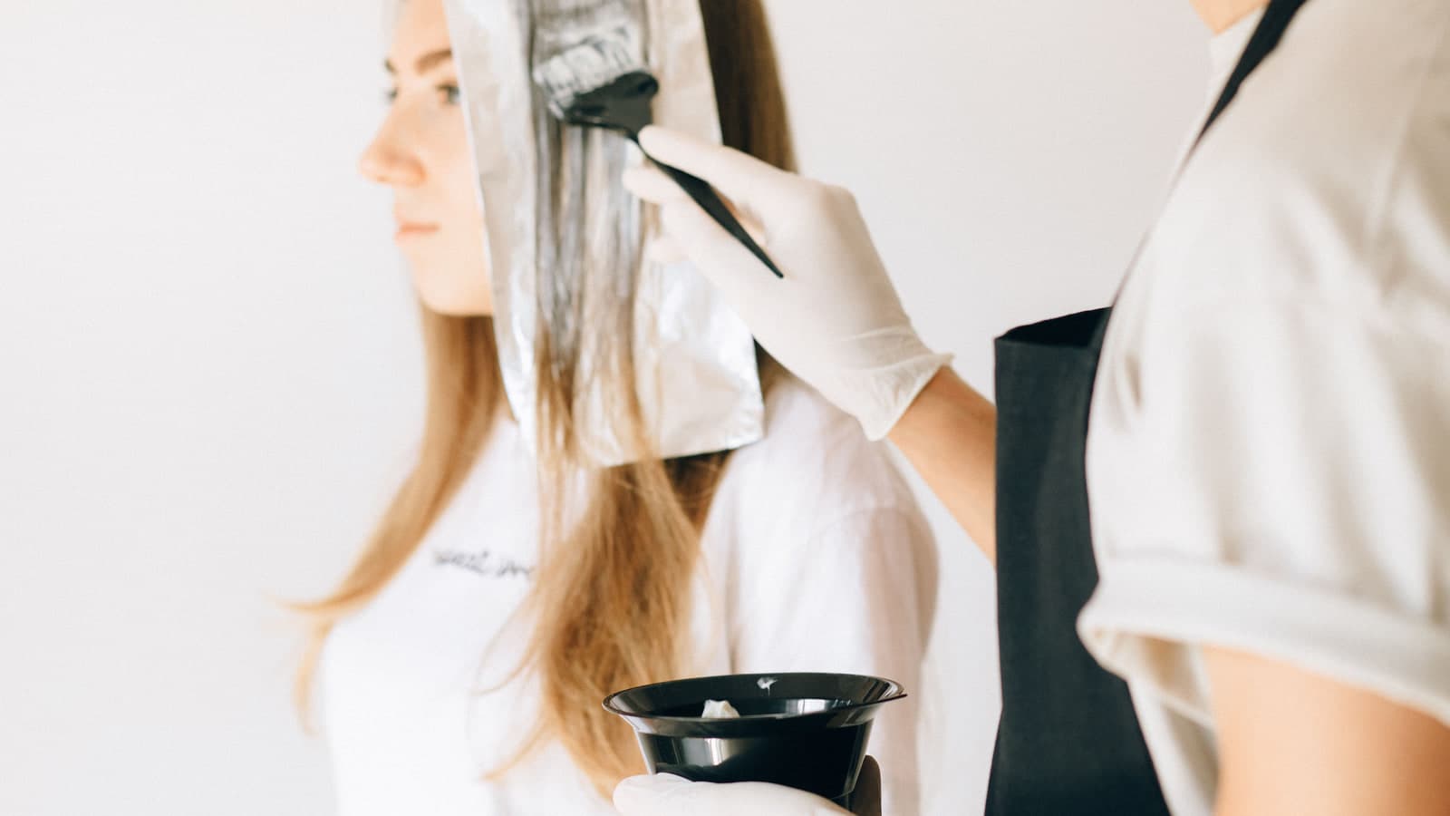 A stylist applying hair colour with a brush and foil