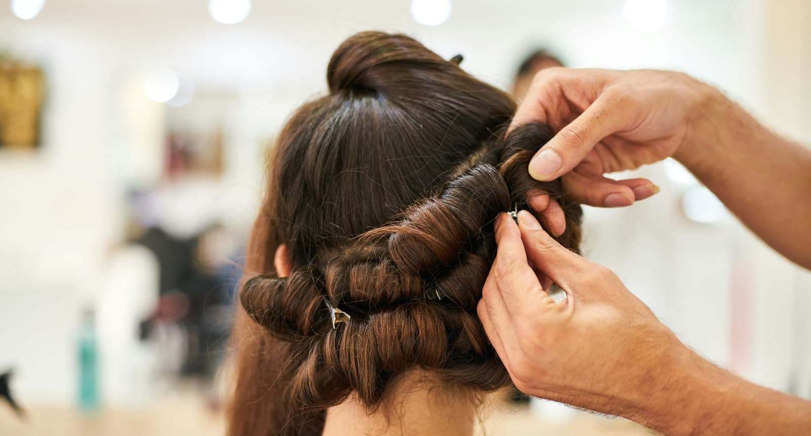 A hairstylist pinning a client’s updo